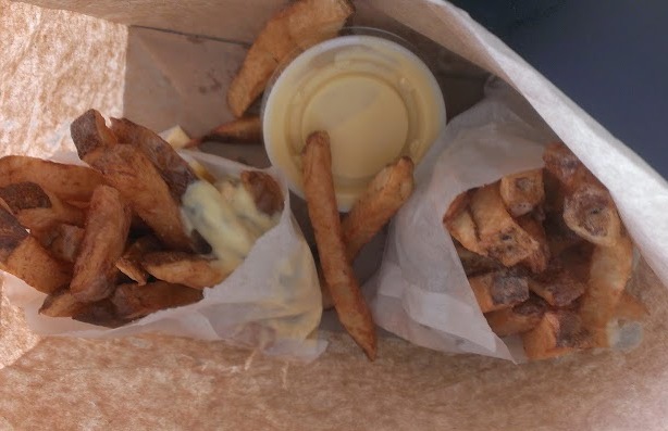French fries in a paper bag with sauces